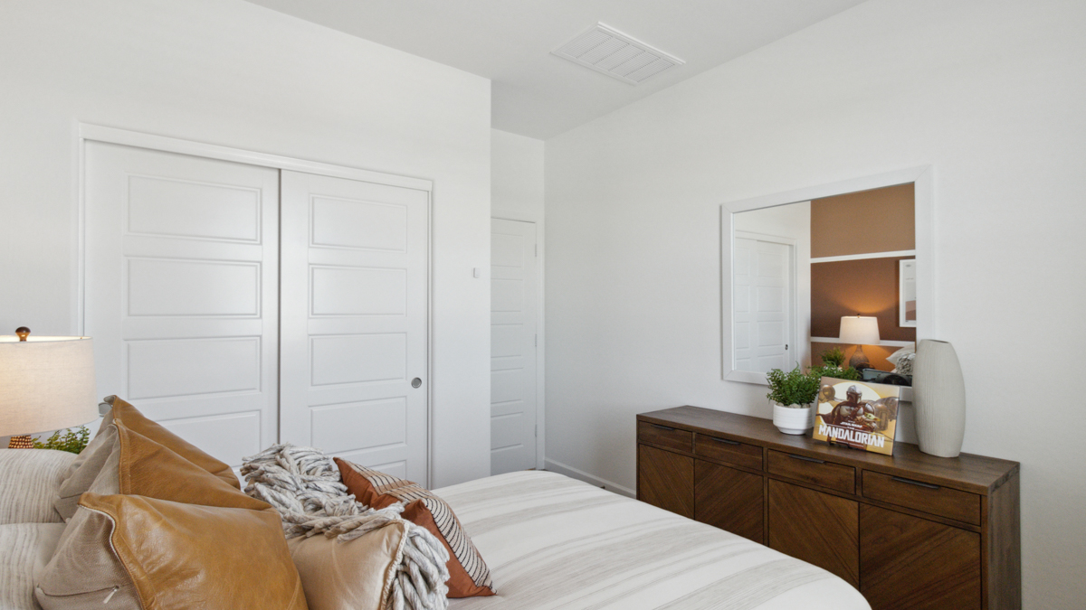A vibrant kids' bedroom showcasing a neatly made bed, a stylish dresser, and a playful painting that adds charm.
