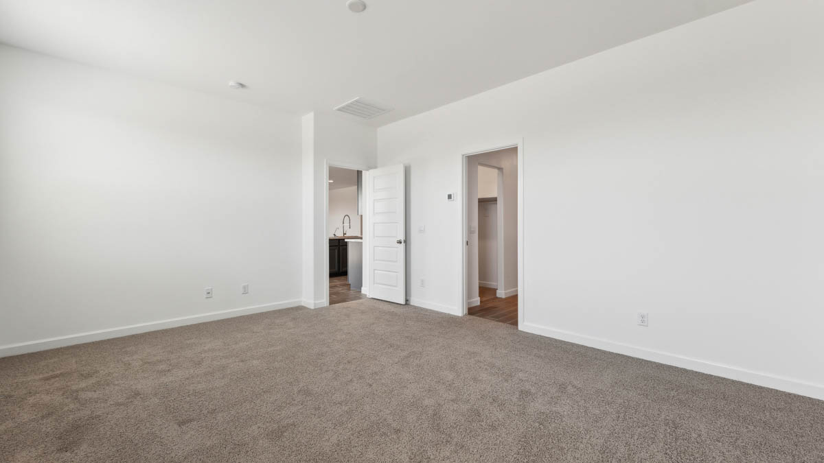 Large primary bedroom with carpet, large window, and primary bathroom connected.