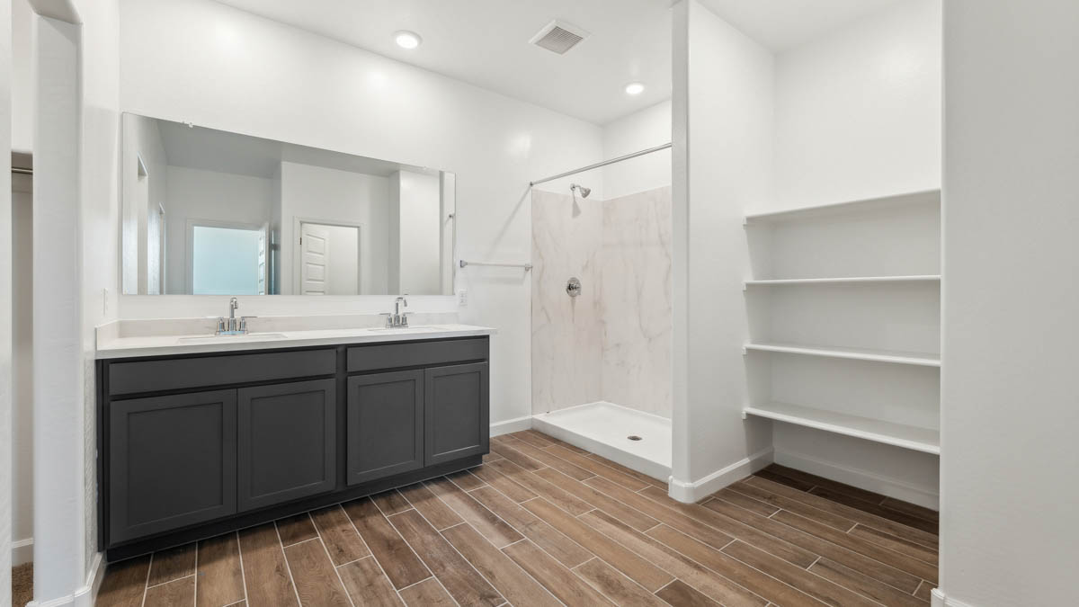Large primary bathroom with dual sinks, shower, and shelving.