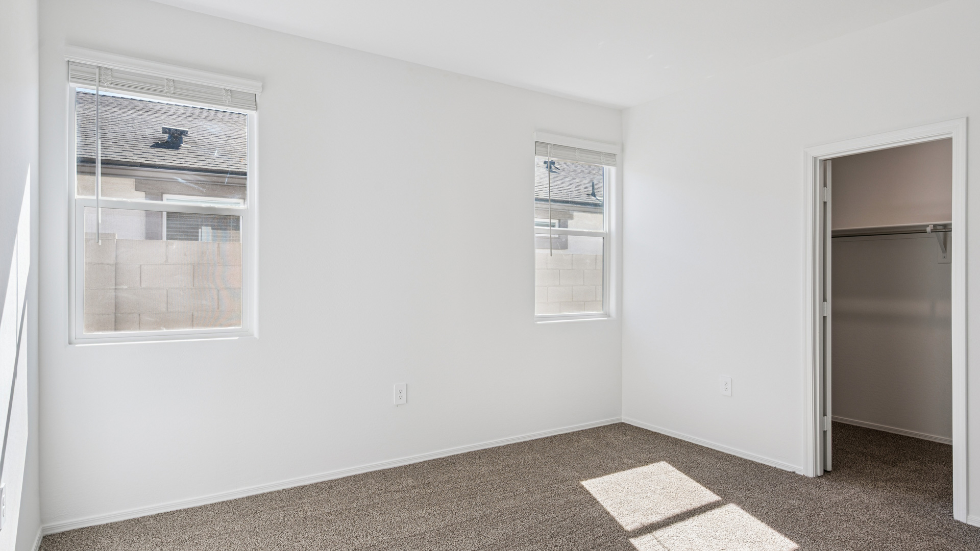 A spacious primary bedroom emphasizing open space and natural lighting.