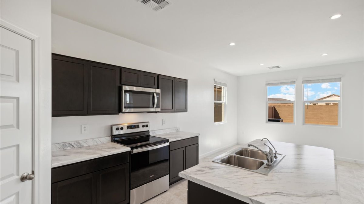 Bright and spacious kitchen with porcelain countertops, stainless steel appliances, and an island with bar seating.