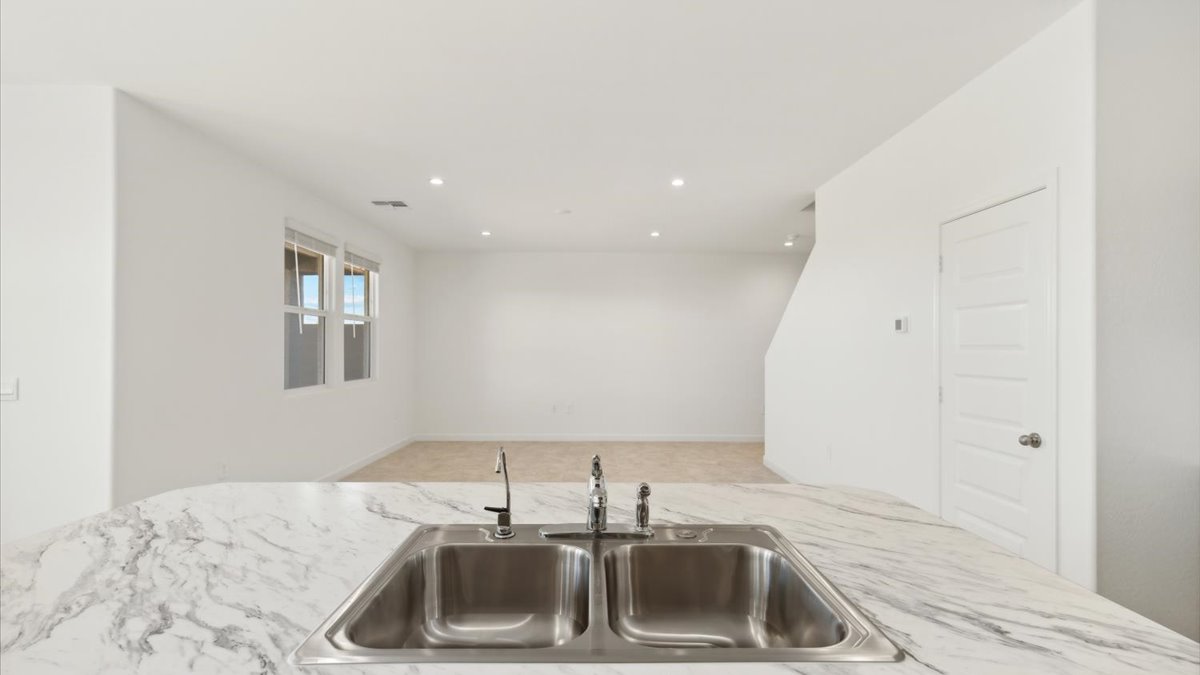 Bright and spacious kitchen with porcelain countertops, stainless steel appliances, and an island with bar seating.