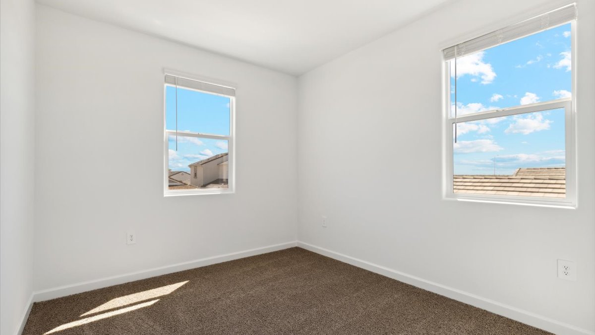 Comfortable guest bedroom featuring neutral-toned walls, large closet and two windows.
