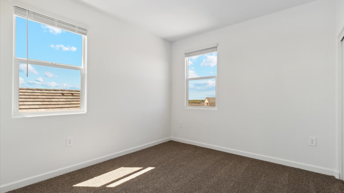 Comfortable guest bedroom featuring neutral-toned walls, large closet and two windows.