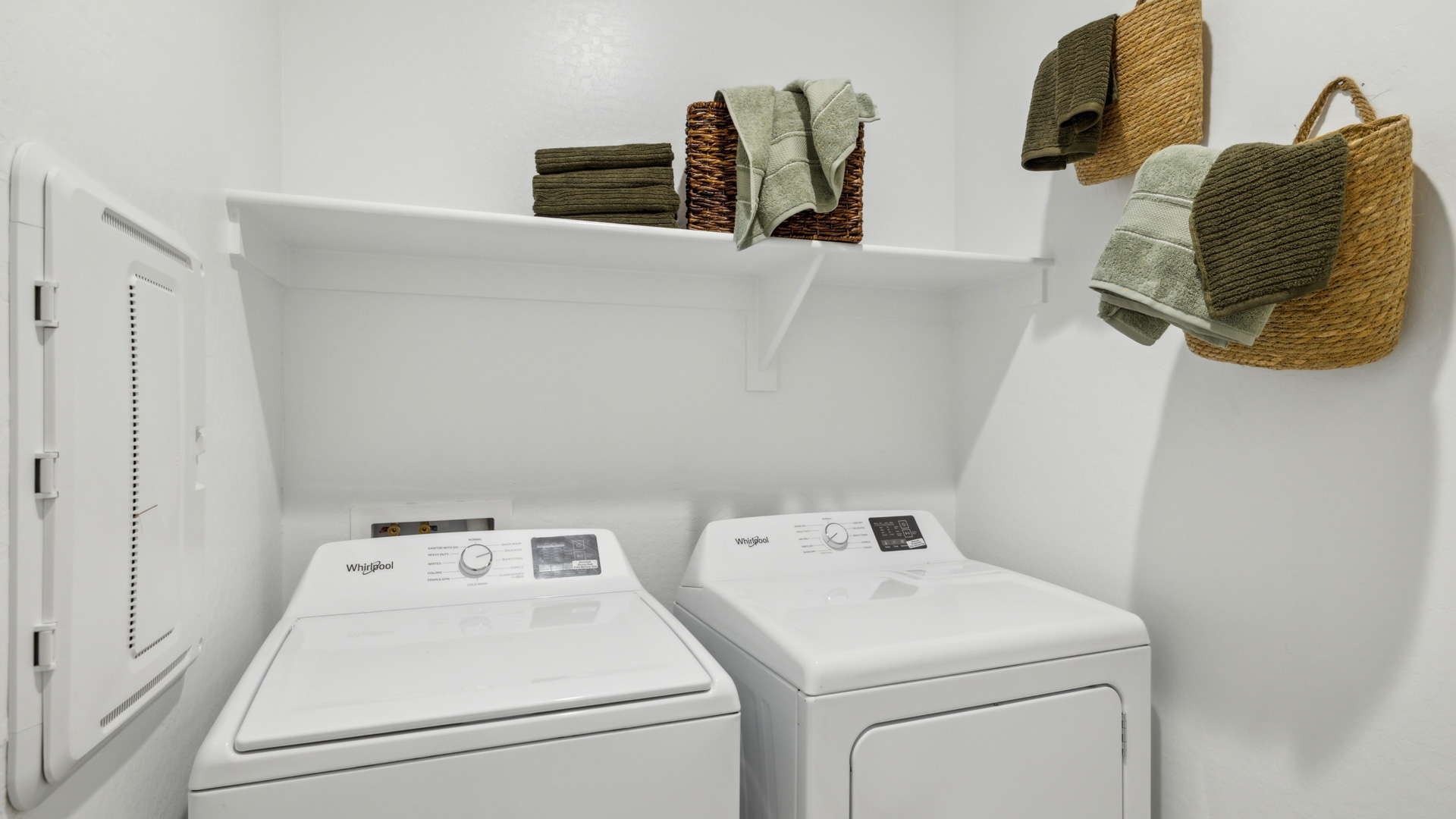 Spacious laundry room with washer and dryer connections and shelving for storage.