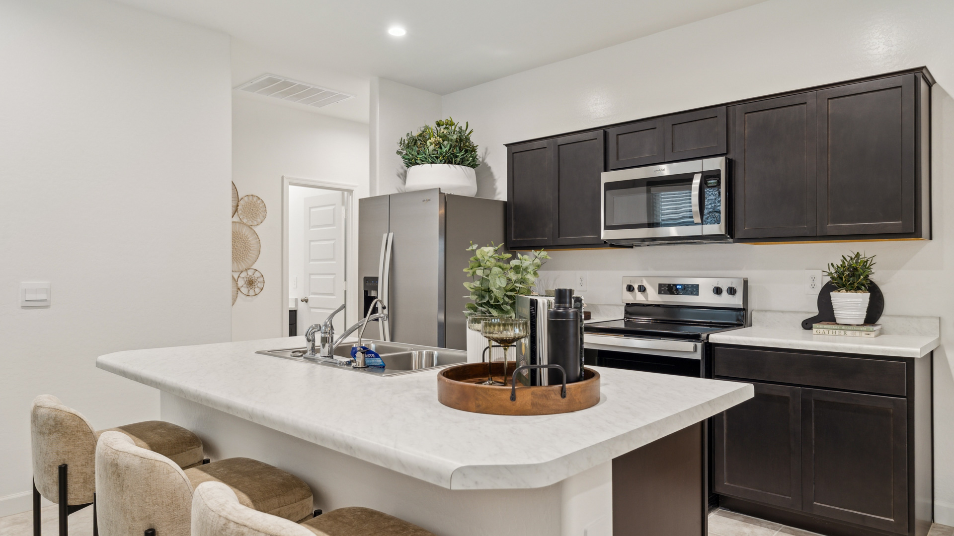 Bright and spacious kitchen with countertops, stainless steel appliances, and an island with bar seating.
