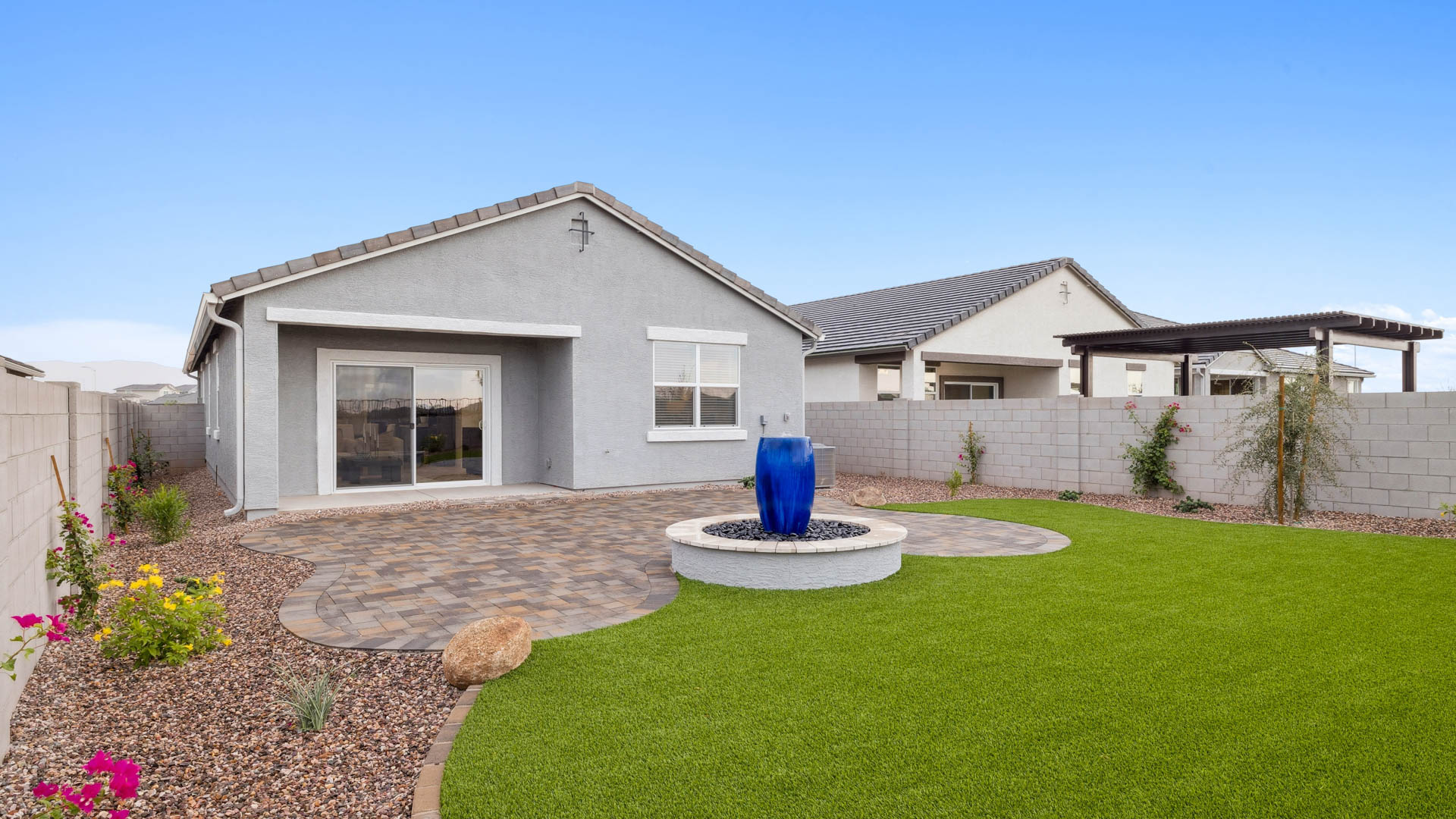 Outdoor covered patio with seating area overlooking a well-maintained lawn, perfect for relaxation.