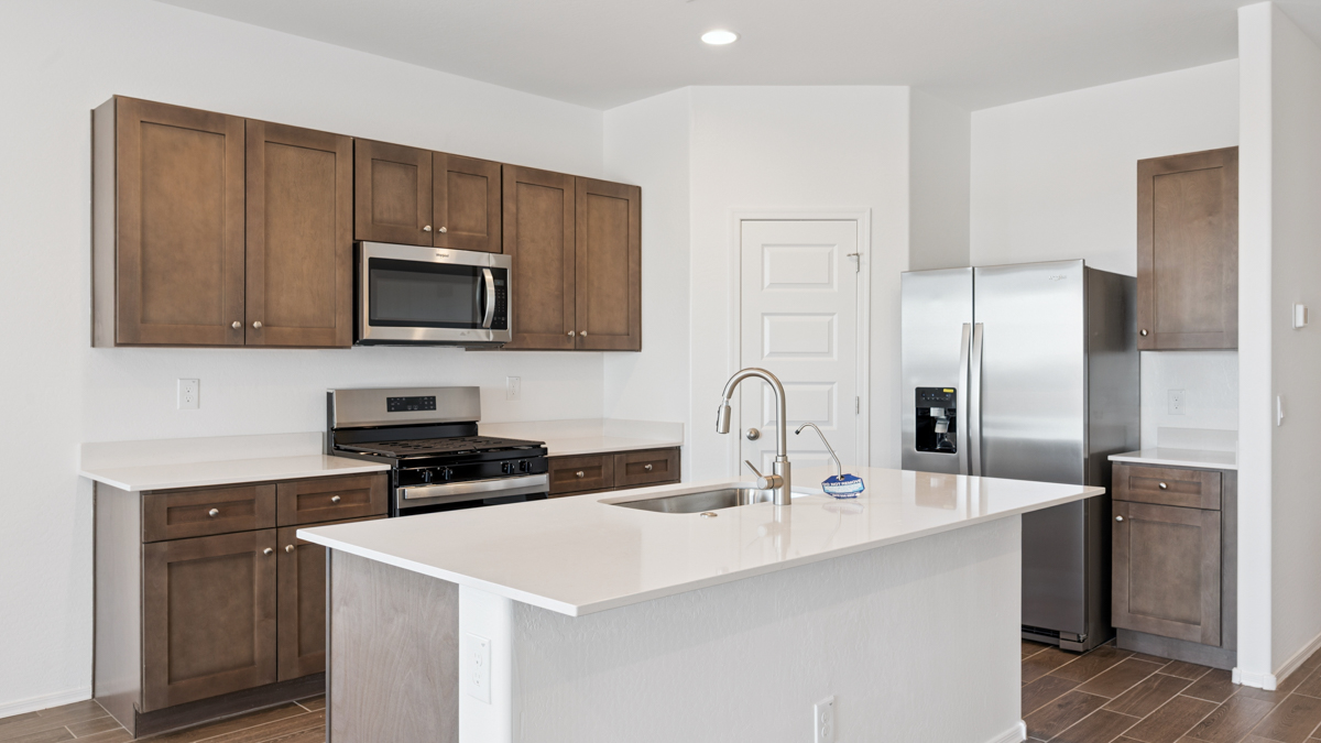 Bright and spacious kitchen with quartz countertops, stainless steel appliances, and an island with bar seating.