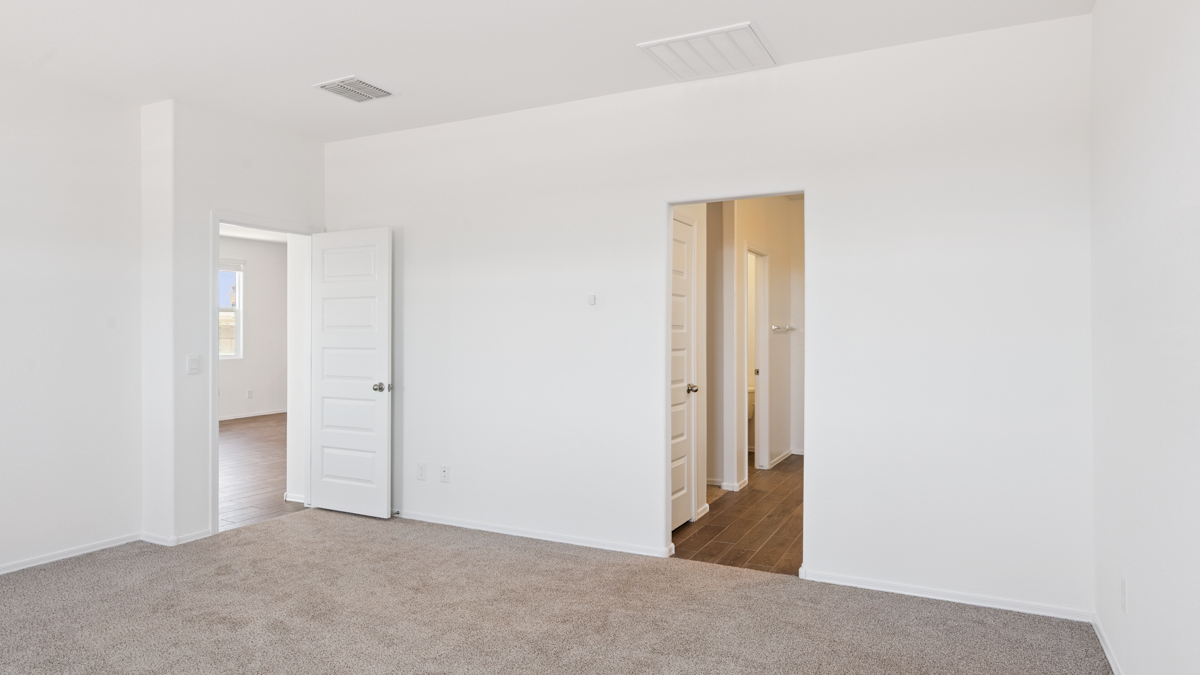 A spacious primary bedroom emphasizing open space and natural lighting.