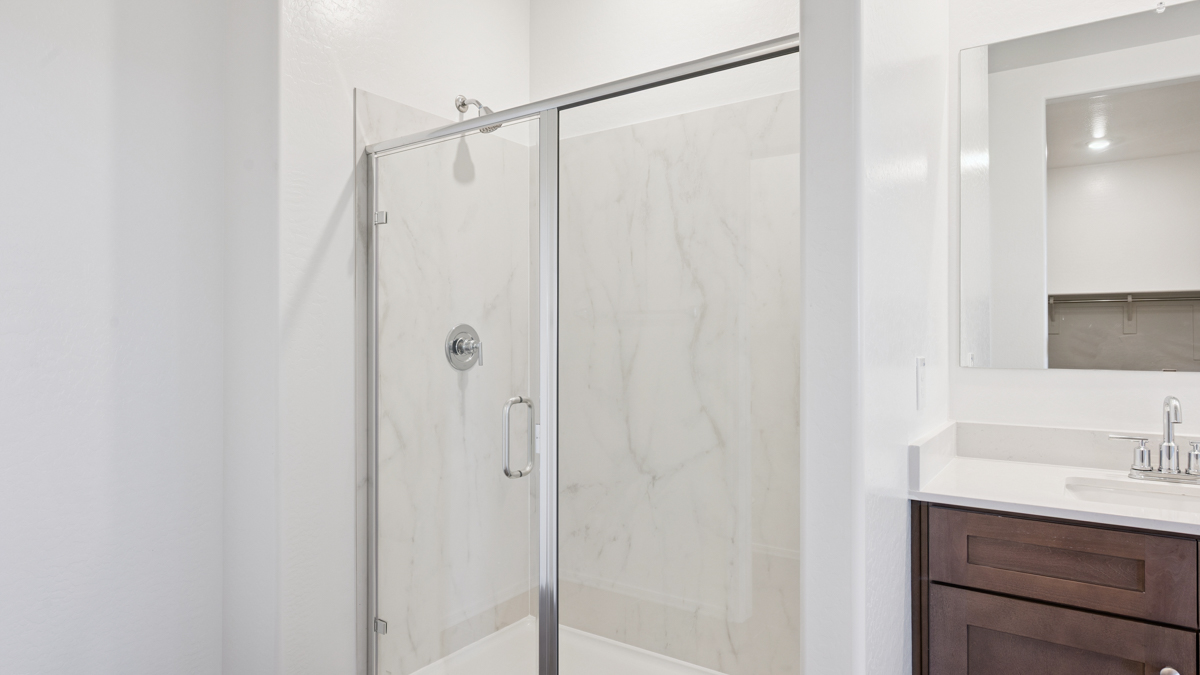 Modern primary bathroom with double vanities, quartz countertops with a walk-in shower and a walk-in closet.
