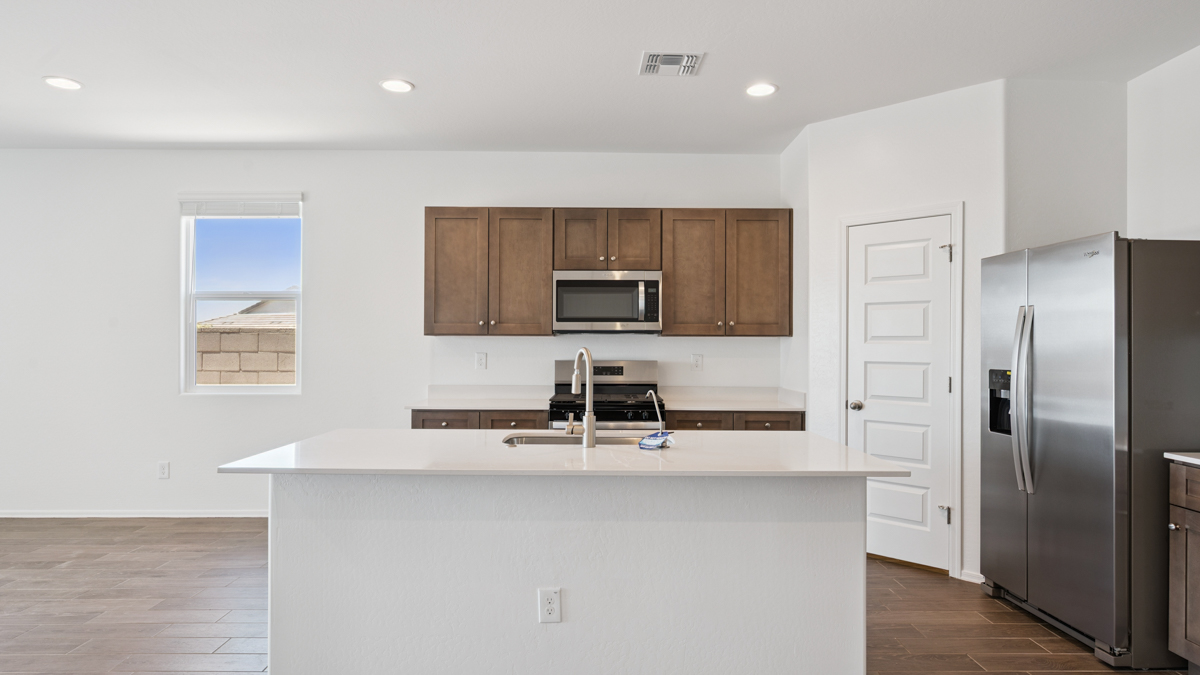 Bright and spacious kitchen with quartz countertops, stainless steel appliances, and an island with bar seating.