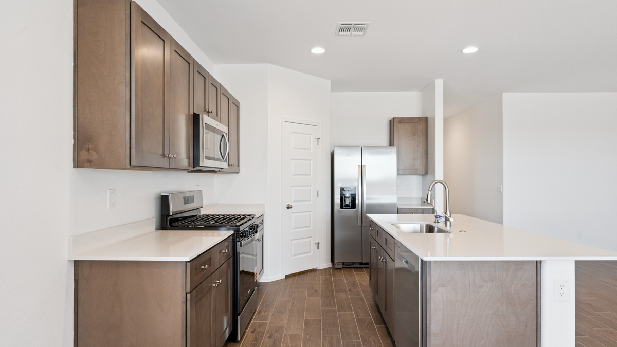 Bright and spacious kitchen with quartz countertops, stainless steel appliances, and an island with bar seating.