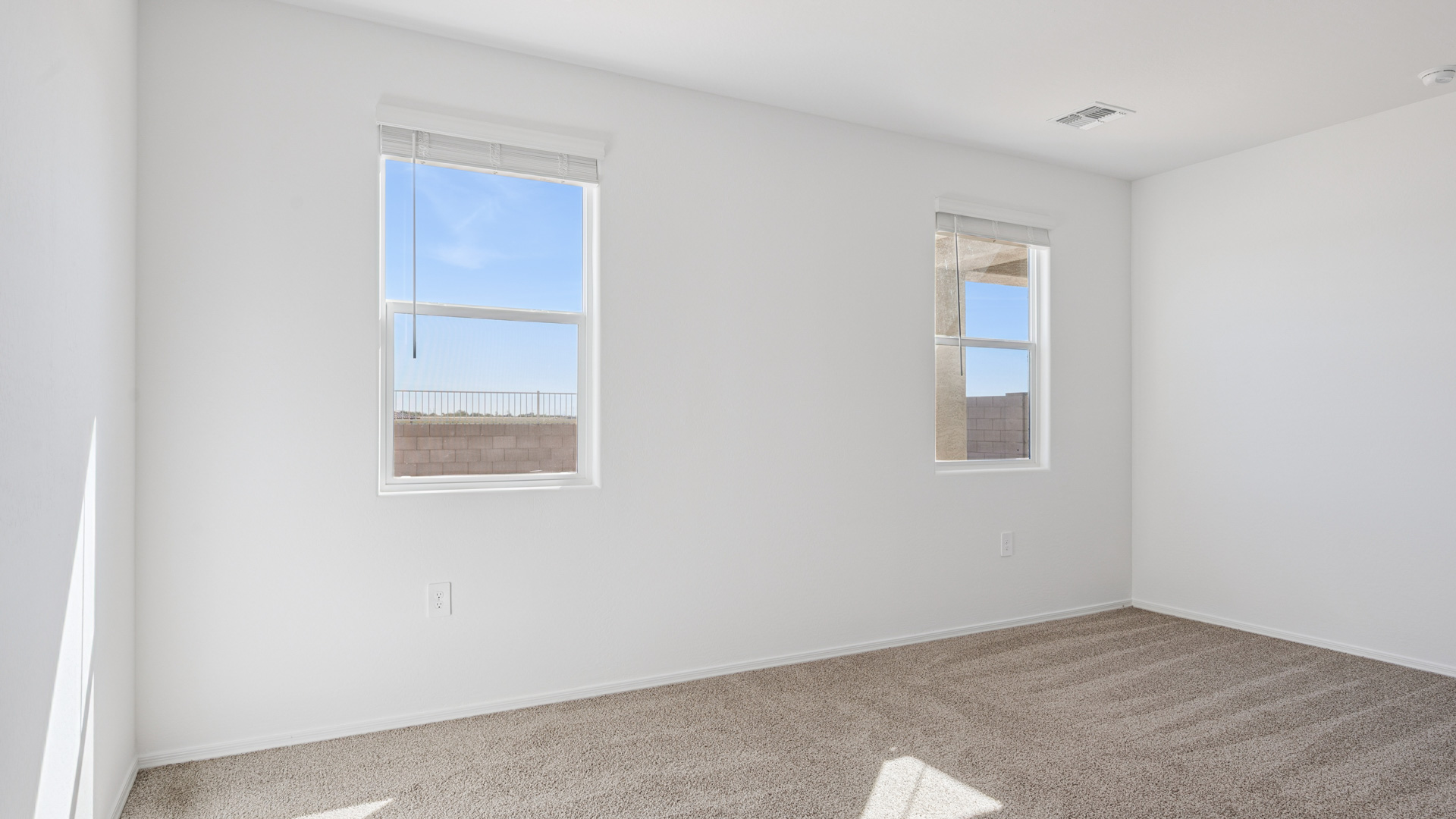 A spacious primary bedroom emphasizing open space and natural lighting.