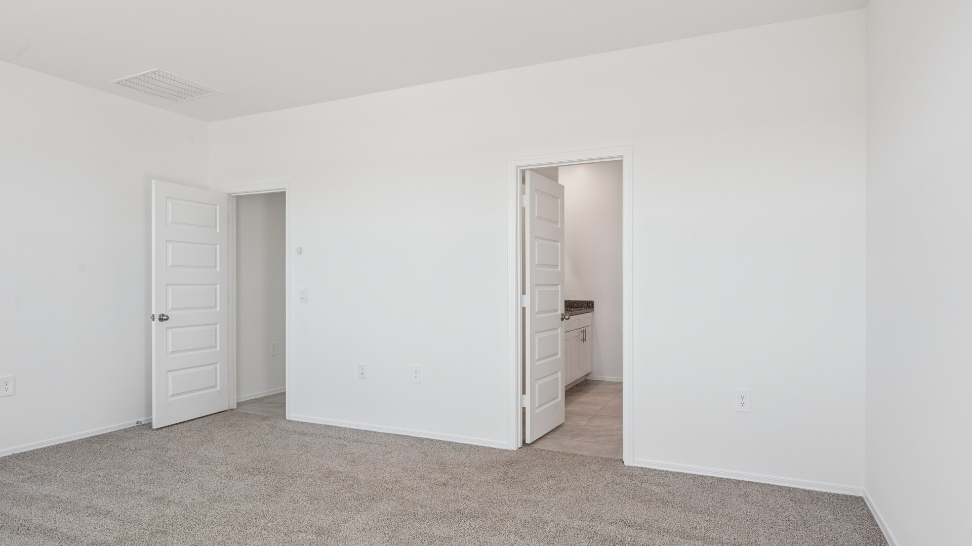 A spacious primary bedroom emphasizing open space and natural lighting.