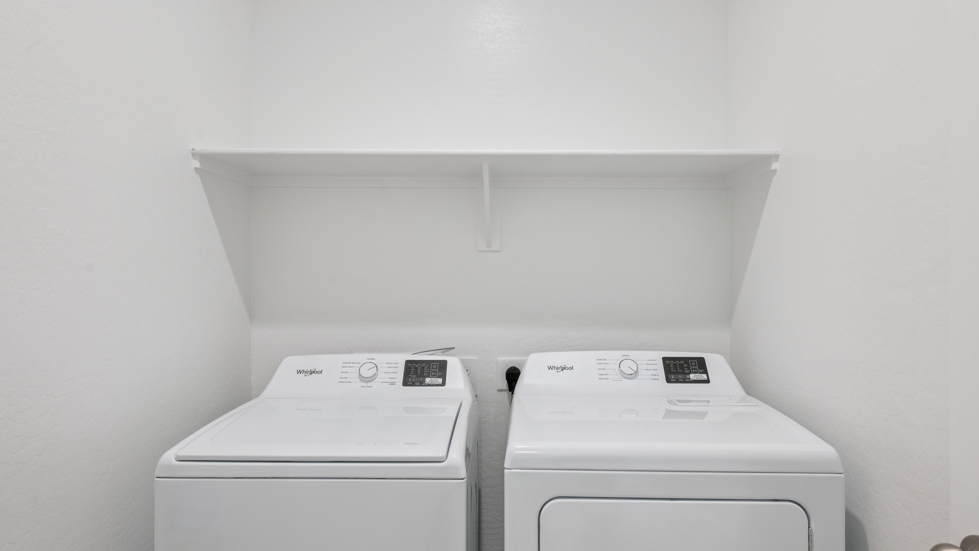 Spacious laundry room with washer and dryer connections and shelving for storage.