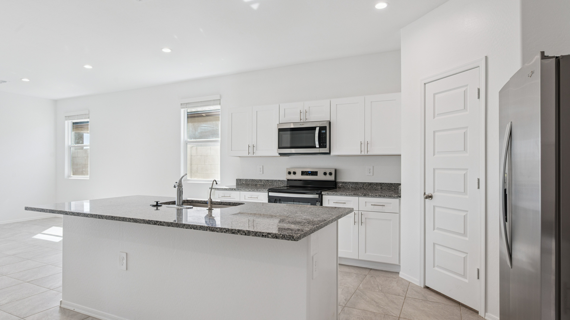 Bright and spacious kitchen with granite countertops, stainless steel appliances, and an island with bar seating.