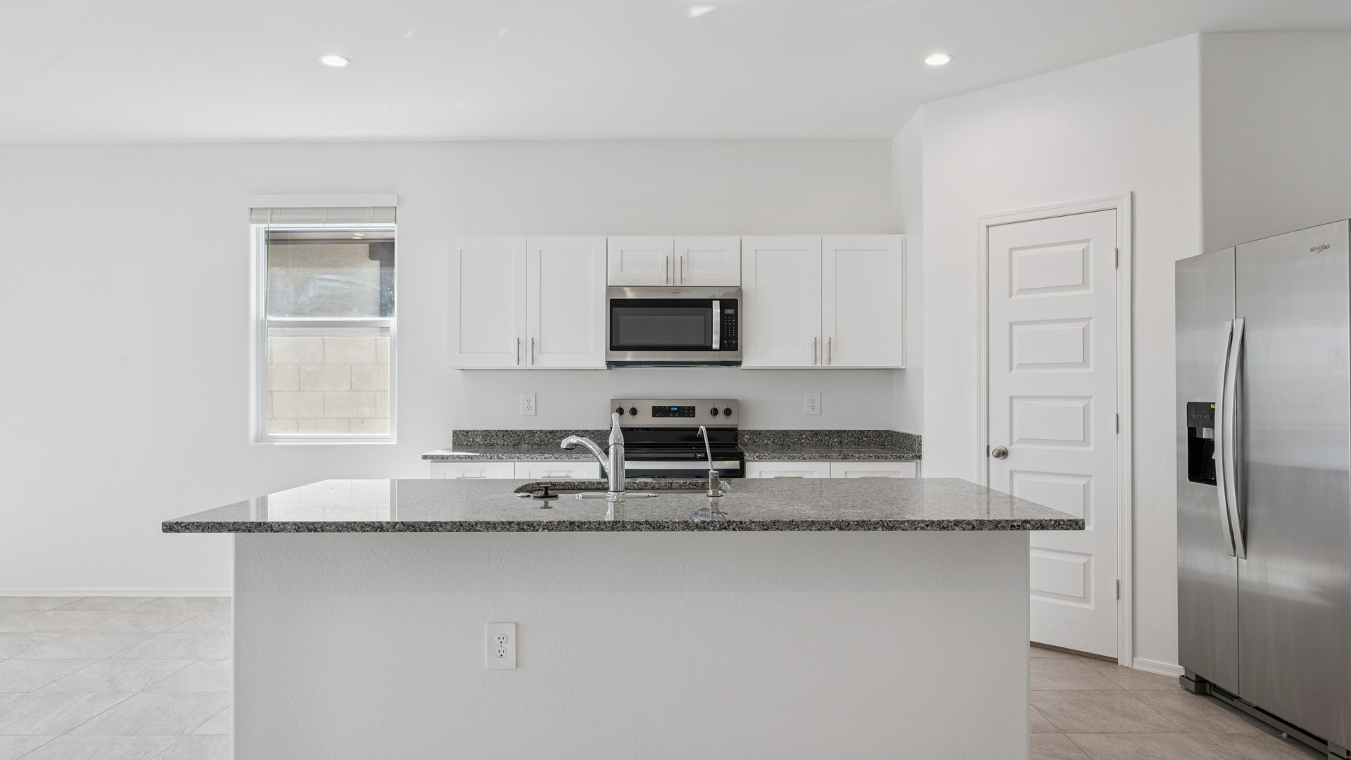 Bright and spacious kitchen with granite countertops, stainless steel appliances, and an island with bar seating.