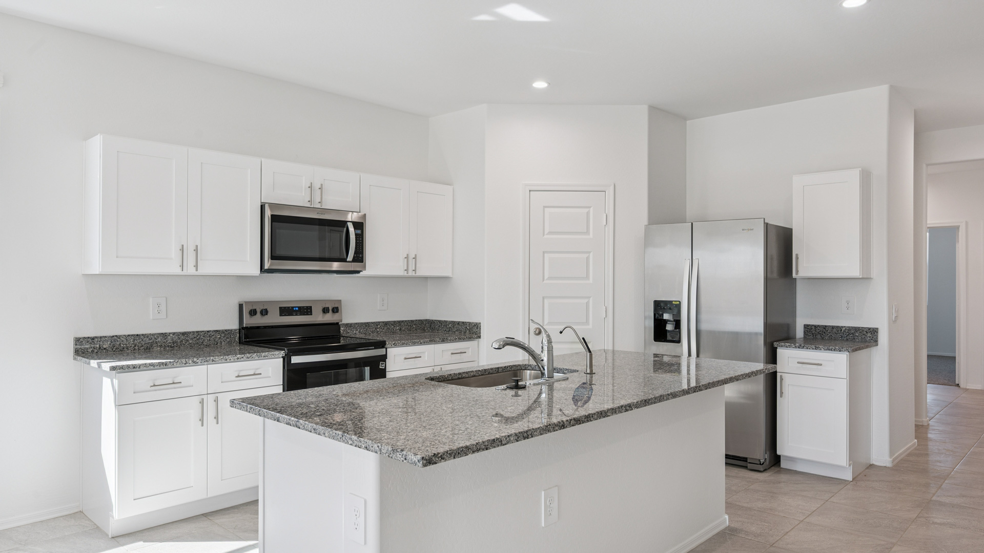 Bright and spacious kitchen with granite countertops, stainless steel appliances, and an island with bar seating.