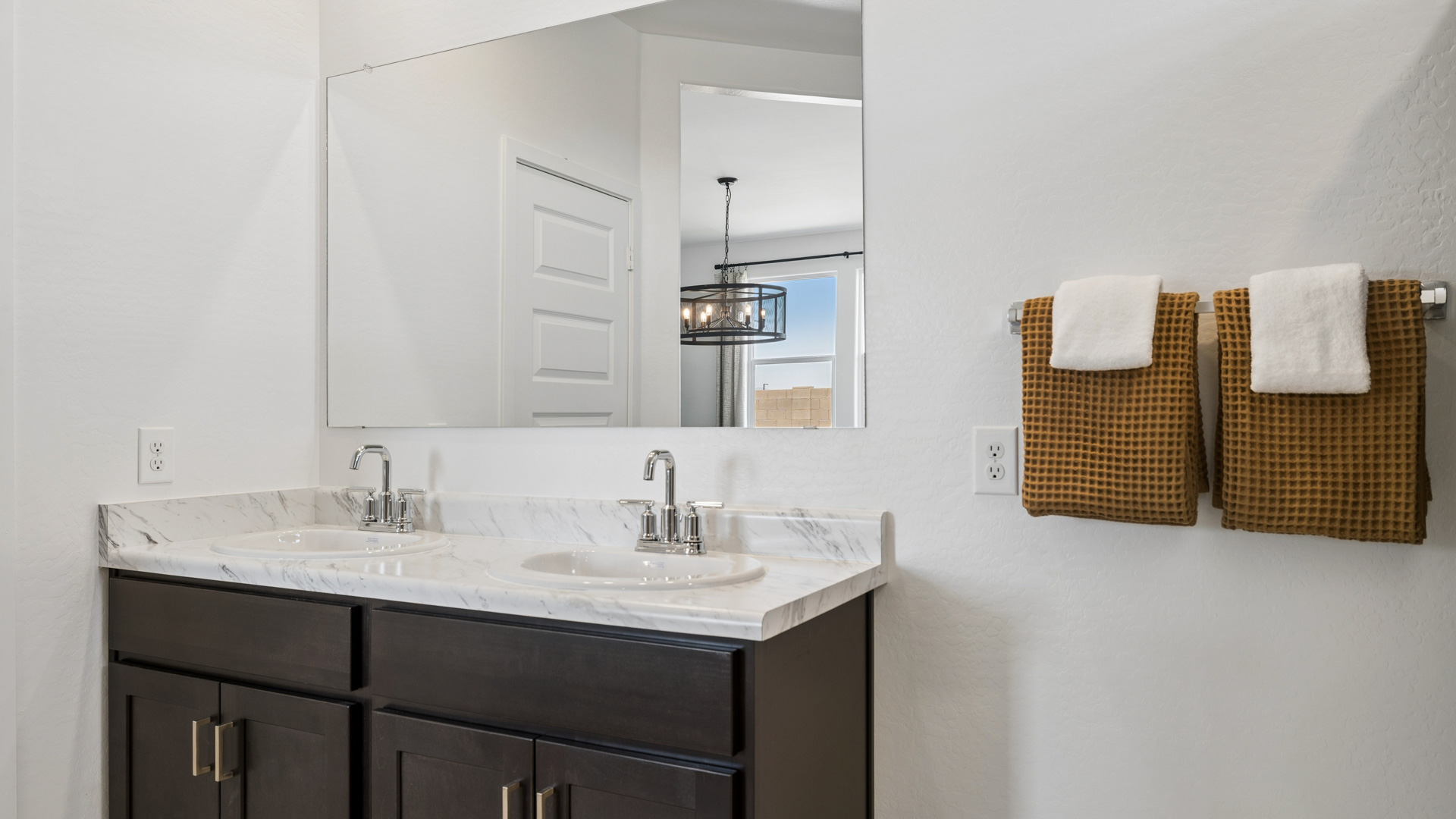 Modern primary bathroom with double vanities, porcelain countertops with a walk-in shower and a walk-in closet.