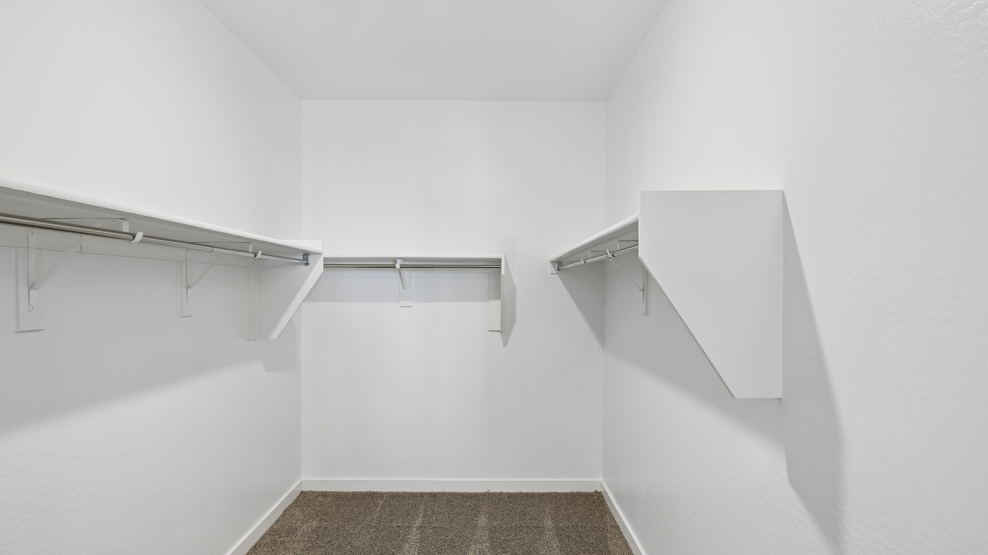 Modern primary bathroom with double vanities, porcelain countertops with a walk-in shower and a walk-in closet.