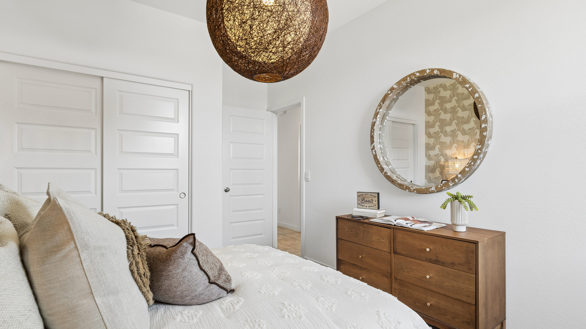 A vibrant kids' bedroom showcasing a neatly made bed, a stylish dresser, and a playful painting that adds charm.