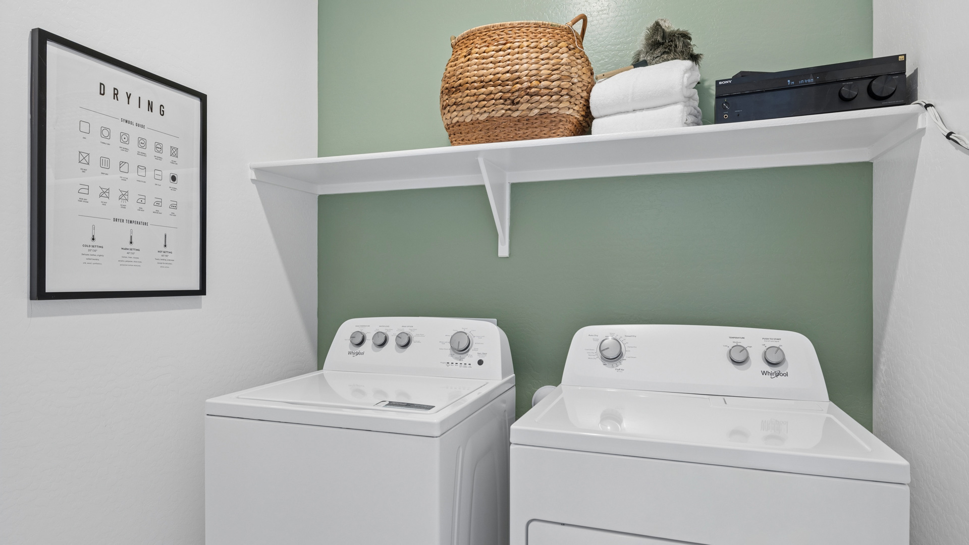 Spacious laundry room with washer and dryer connections and shelving for storage.