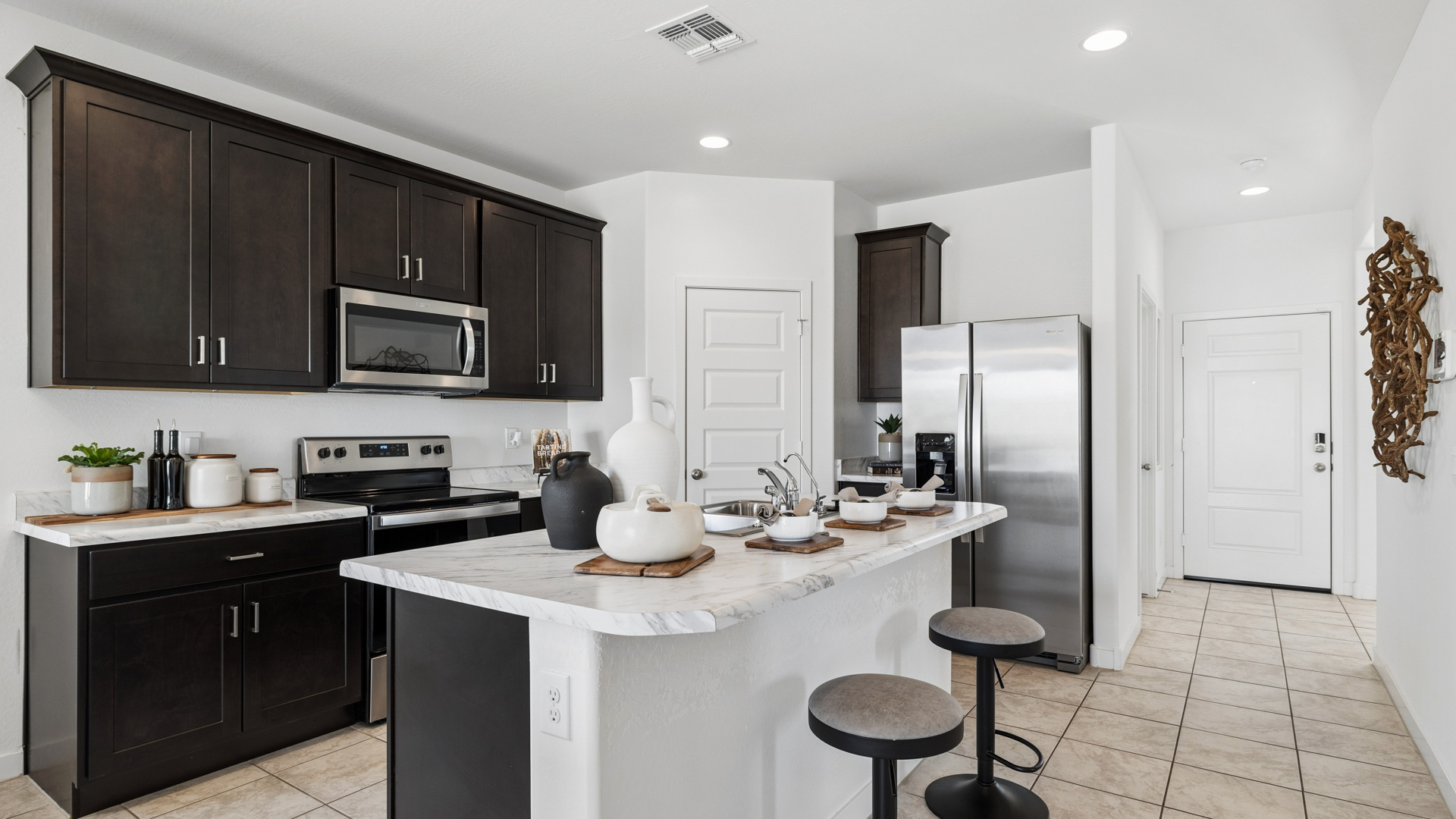 Bright and spacious kitchen with porcelain countertops, stainless steel appliances, and an island with bar seating.