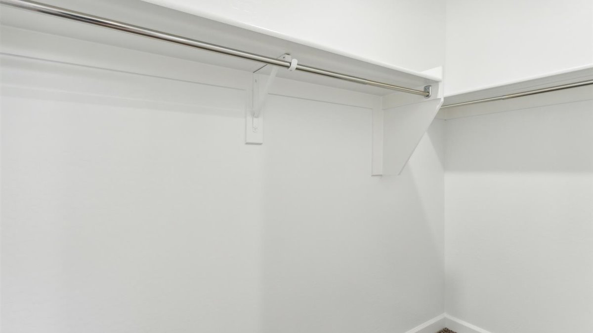 Modern primary bathroom with double vanity, granite countertops with a walk-in shower and a walk-in closet.