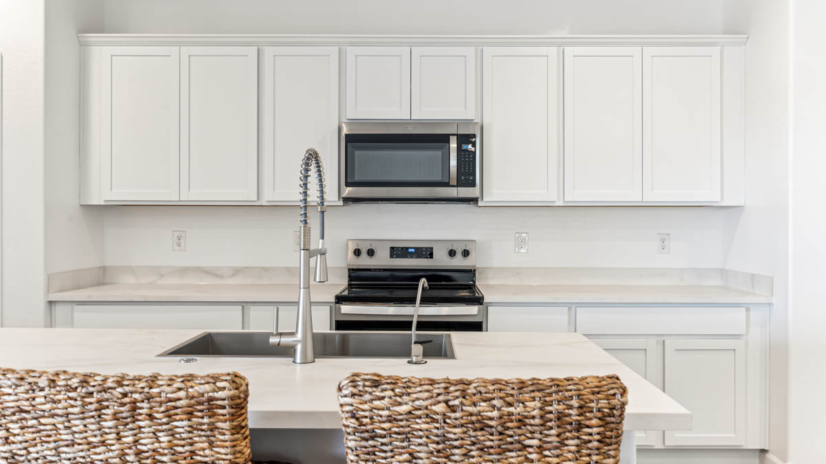 Bright and spacious kitchen with porcelain countertops, stainless steel appliances, and an island with bar seating.