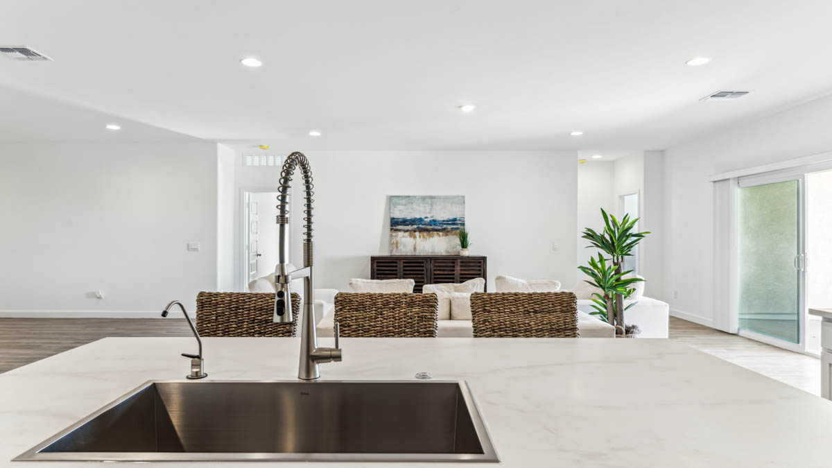 Bright and spacious kitchen with porcelain countertops, stainless steel appliances, and an island with bar seating.