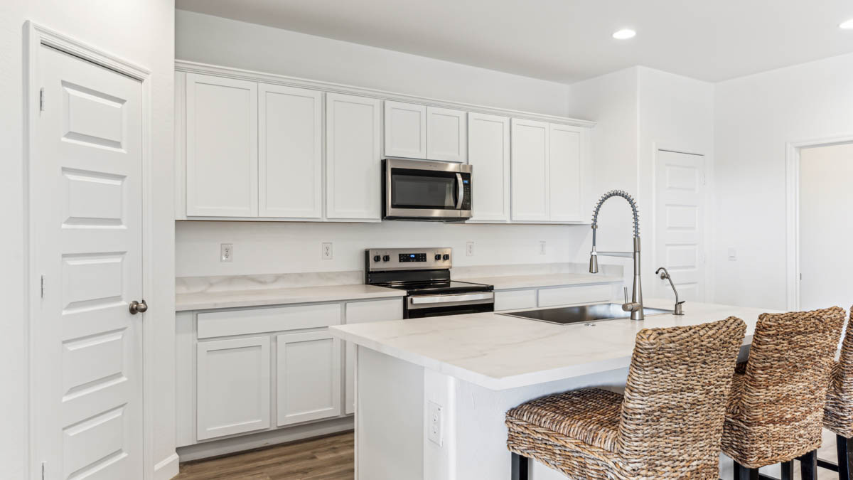 Bright and spacious kitchen with porcelain countertops, stainless steel appliances, and an island with bar seating.