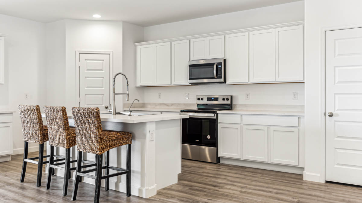 Bright and spacious kitchen with porcelain countertops, stainless steel appliances, and an island with bar seating.