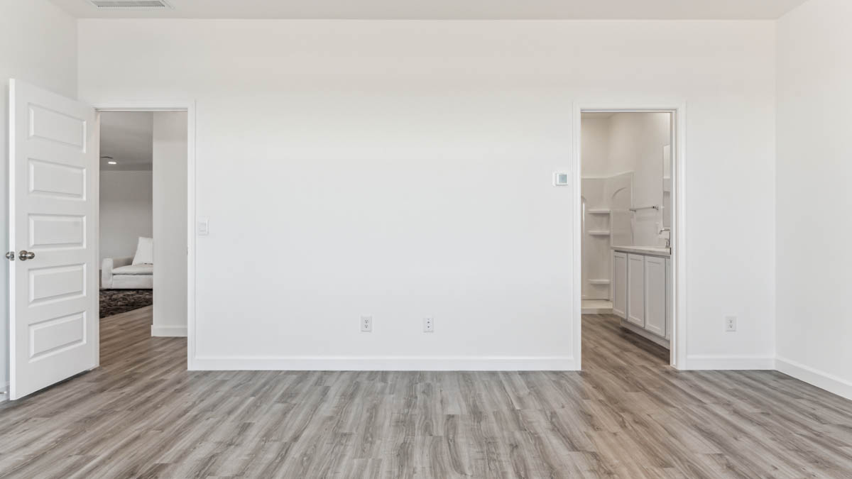 A spacious primary bedroom emphasizing open space and natural lighting.