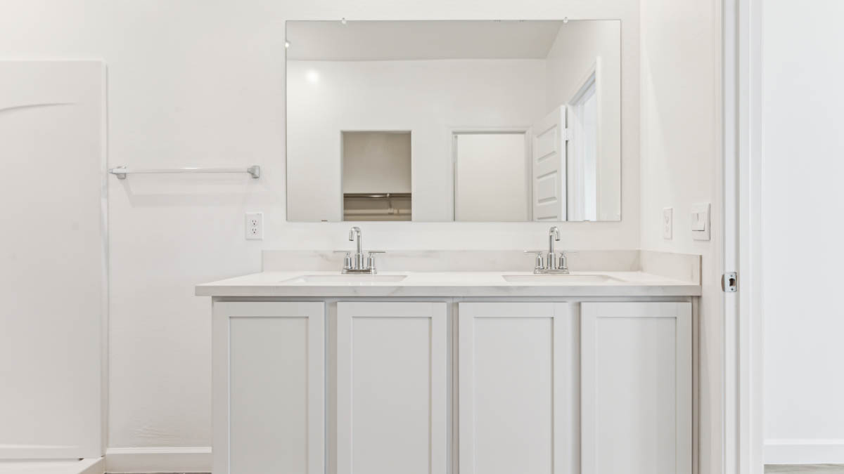 Modern primary bathroom with double vanities, quartz countertops with a walk-in shower and a walk-in closet.
