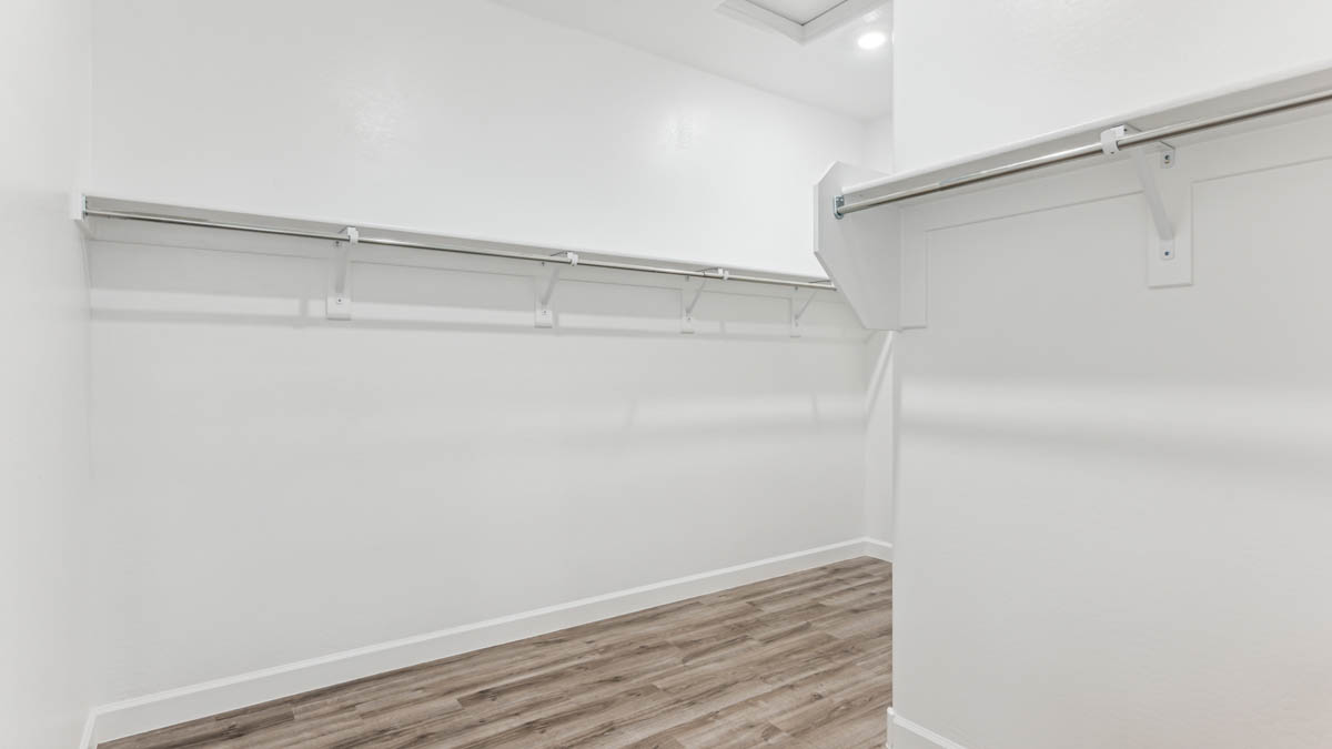 Modern primary bathroom with double vanities, quartz countertops with a walk-in shower and a walk-in closet.