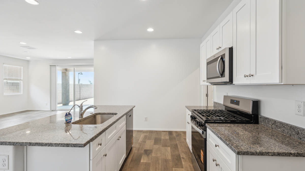 Bright and spacious kitchen with granite countertops, stainless steel appliances, and an island with bar seating.