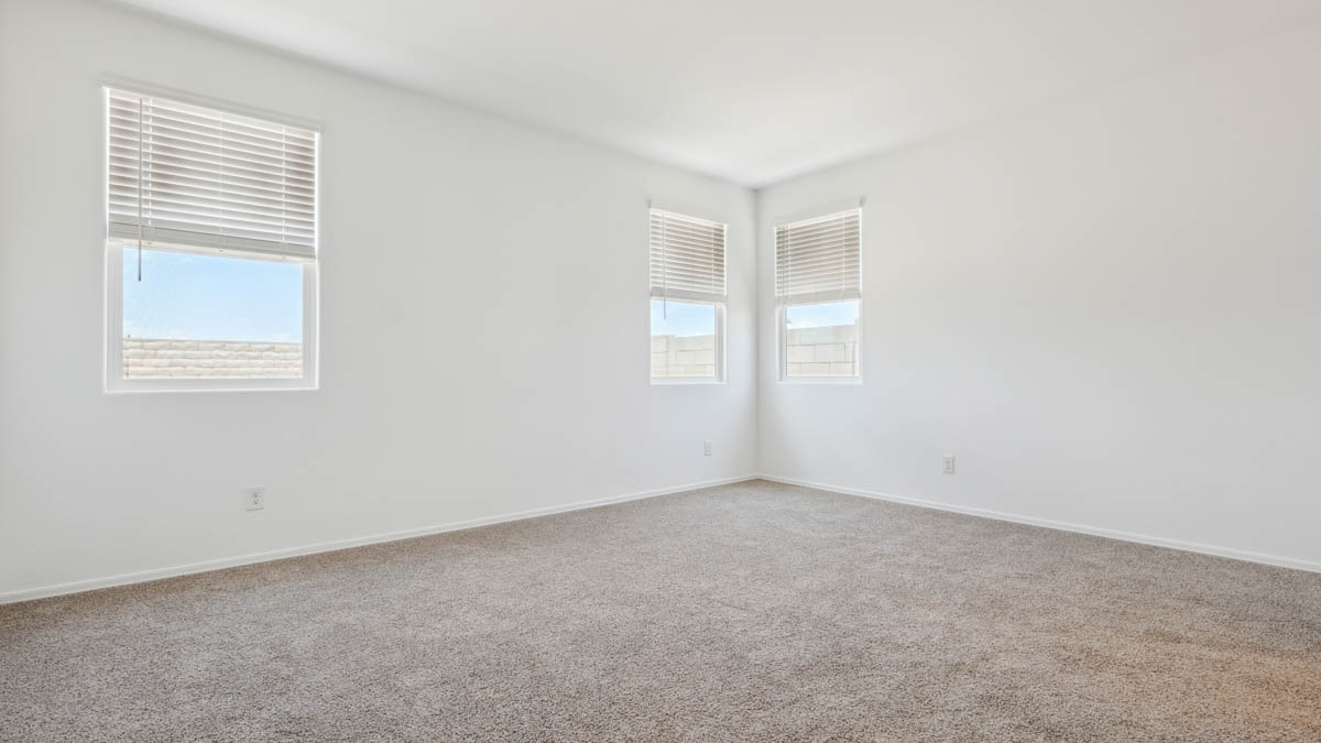 A spacious primary bedroom emphasizing open space and natural lighting.