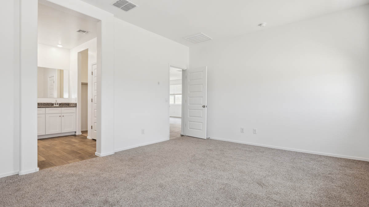 A spacious primary bedroom emphasizing open space and natural lighting.