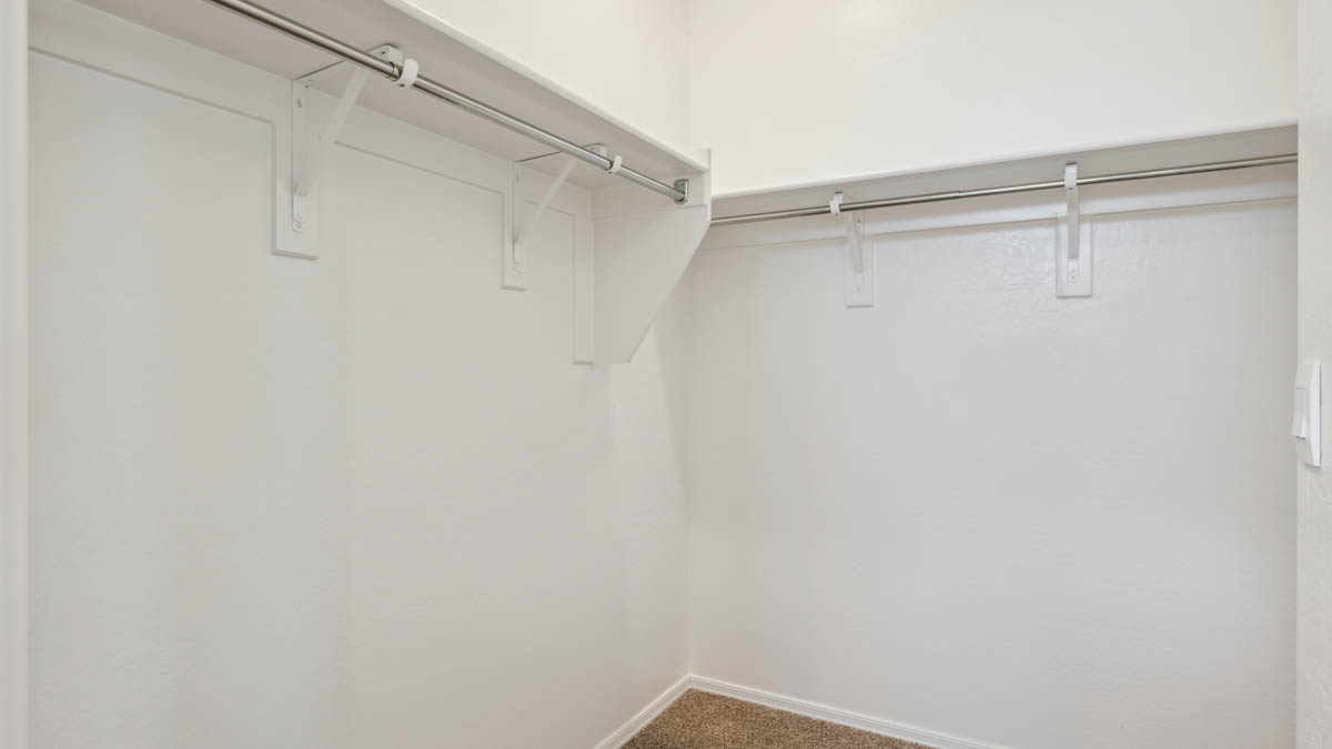Modern primary bathroom with double vanity, granite countertops with a walk-in shower and a walk-in closet.