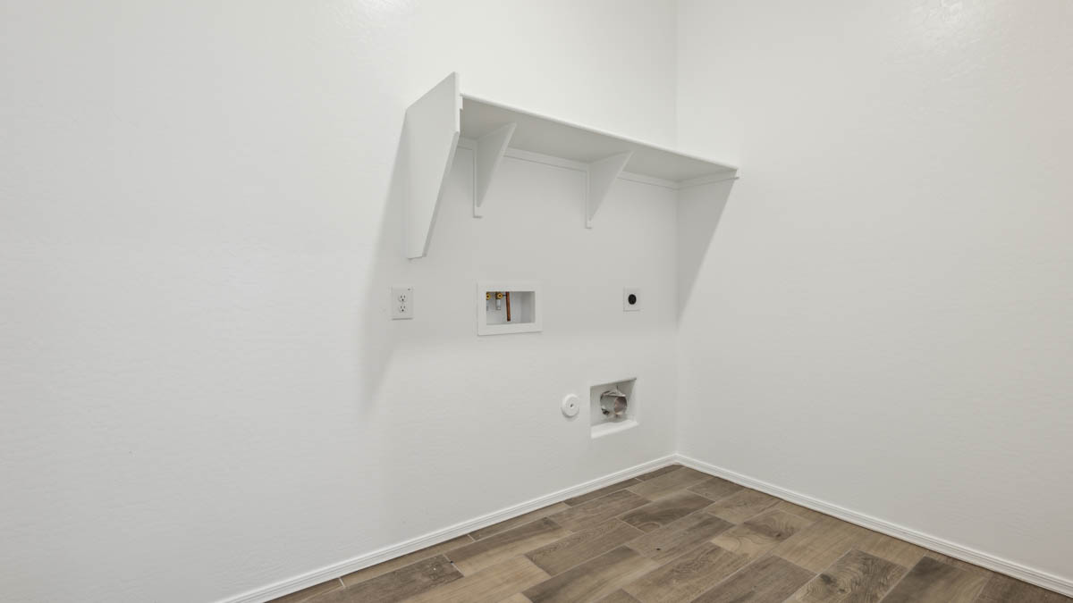 Spacious laundry room with washer and dryer connections and shelving for storage.