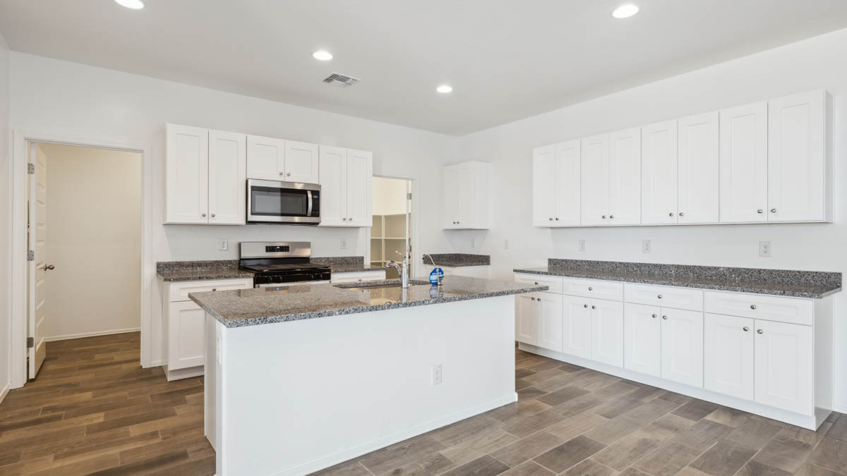 Bright and spacious kitchen with granite countertops, stainless steel appliances, and an island with bar seating.