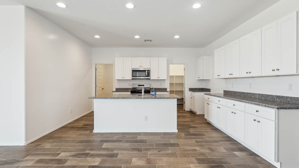 Bright and spacious kitchen with granite countertops, stainless steel appliances, and an island with bar seating.