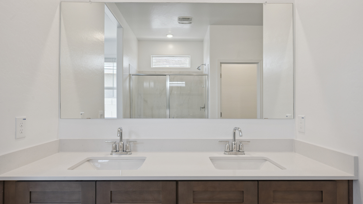 Modern primary bathroom with double vanities, quartz countertops with a walk-in shower and a walk-in closet.