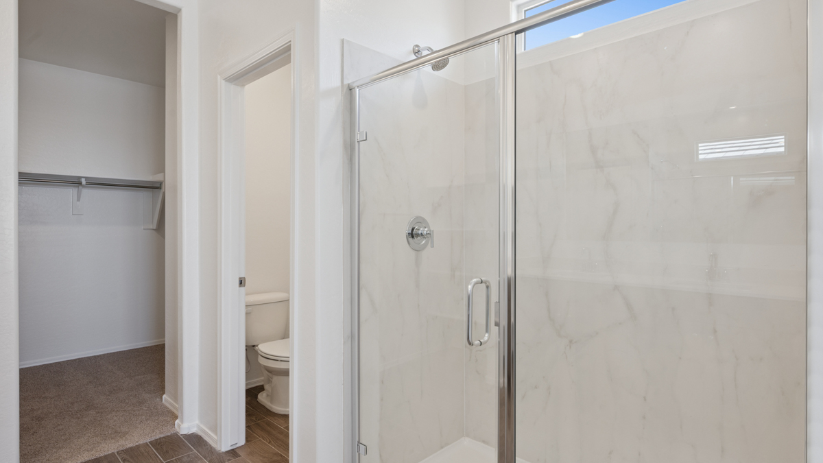 Modern primary bathroom with double vanities, quartz countertops with a walk-in shower and a walk-in closet.