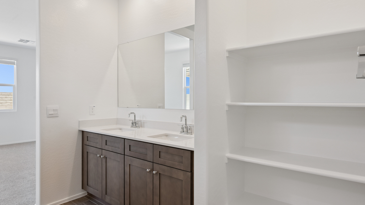 Modern primary bathroom with double vanities, quartz countertops with a walk-in shower and a walk-in closet.