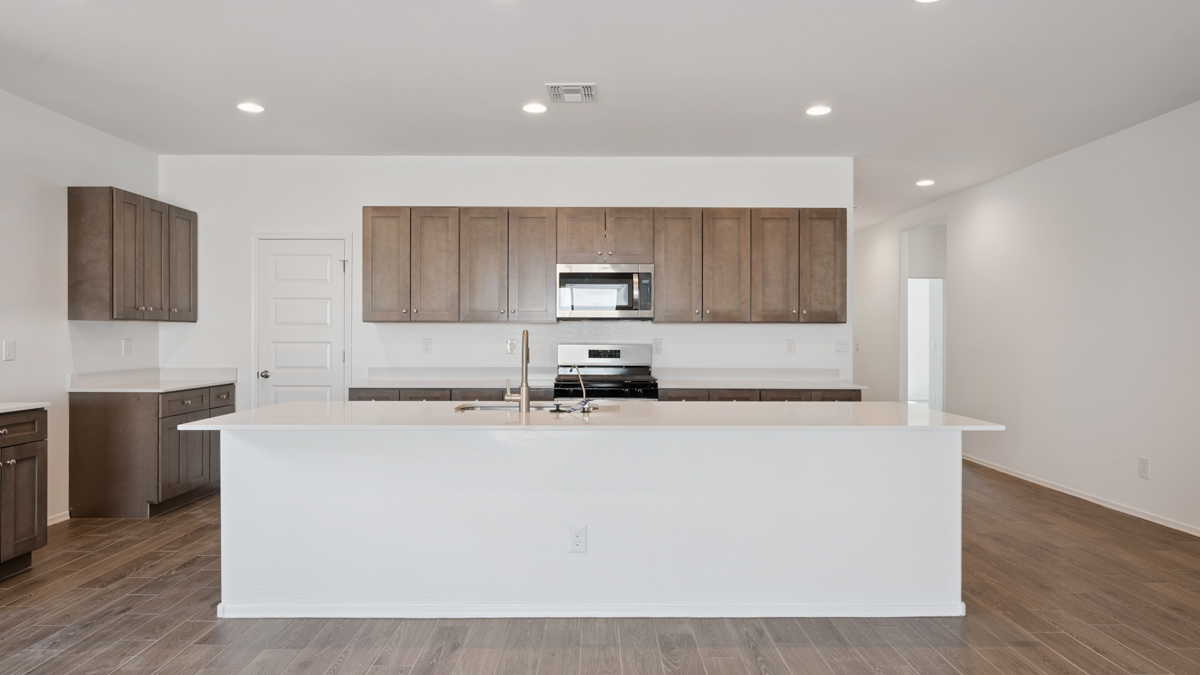 Bright and spacious kitchen with quartz countertops, stainless steel appliances, and an island with bar seating.
