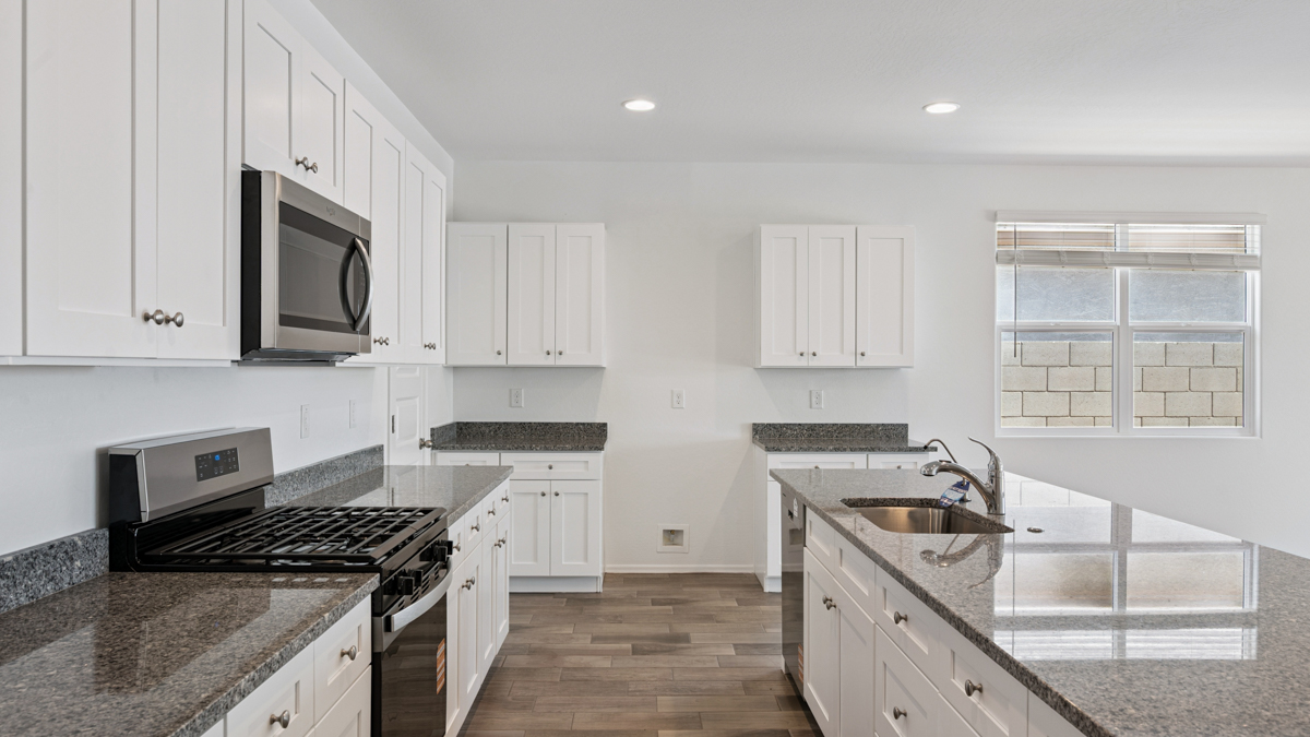 Bright and spacious kitchen with granite countertops, stainless steel appliances, and an island with bar seating.