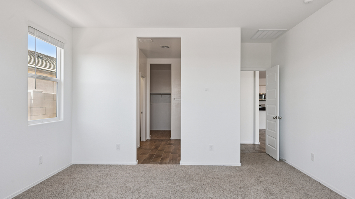 A spacious primary bedroom emphasizing open space and natural lighting.