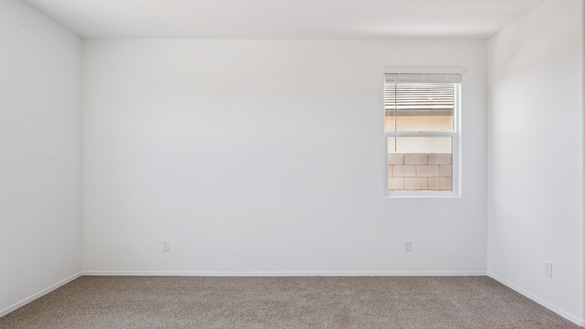 A spacious primary bedroom emphasizing open space and natural lighting.