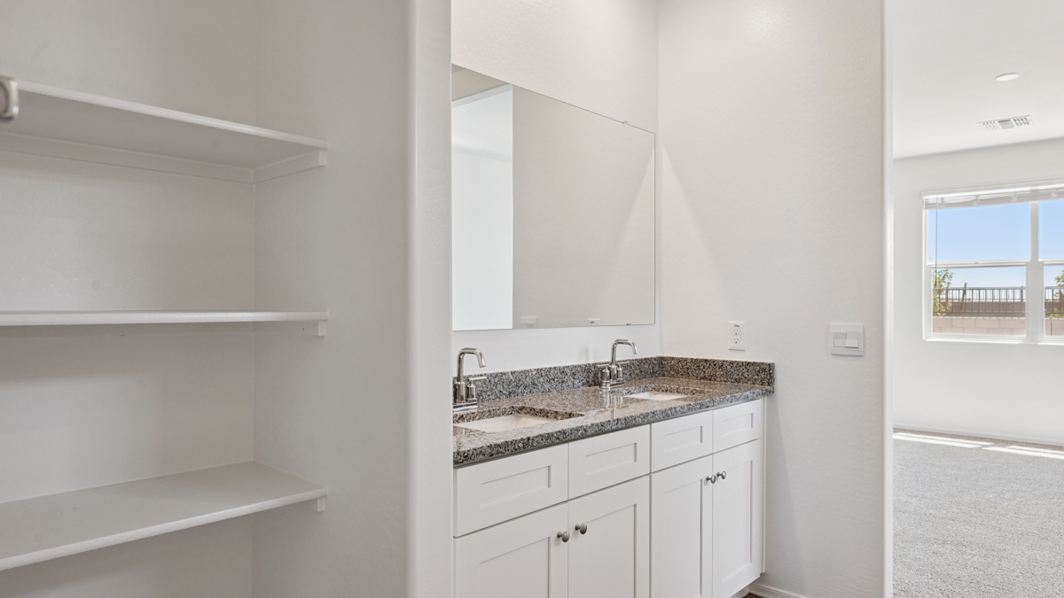 Modern primary bathroom with double vanity, granite countertops with a walk-in shower and a walk-in closet.